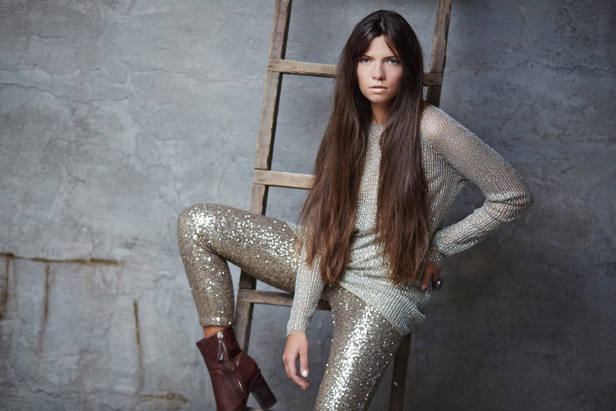 fashionable-woman-with-long-brown-hair-shiny-costume-posing-grey-wall-with-wooden-ladder.jpg