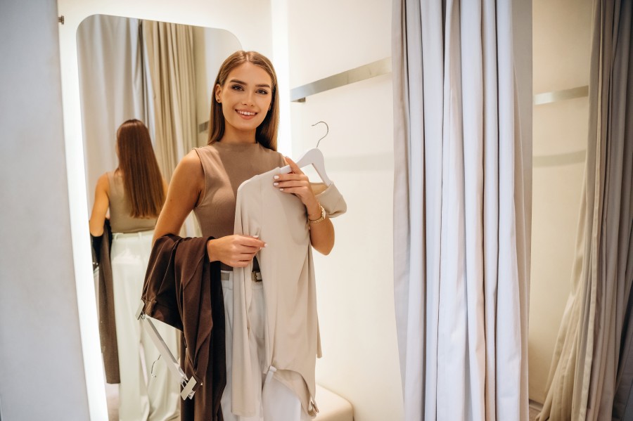standing-holding-sweater-pants-smiling-woman-tries-clothes-store-fitting-room.jpg