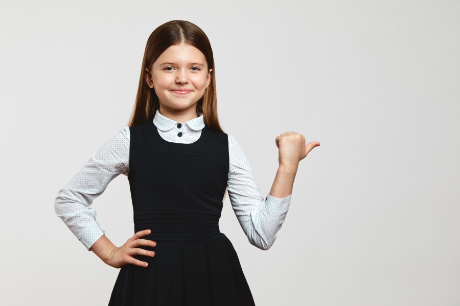 pretty-kid-school-uniform-looking-camera-keeping-hand-waist-pointing-free-space.jpg