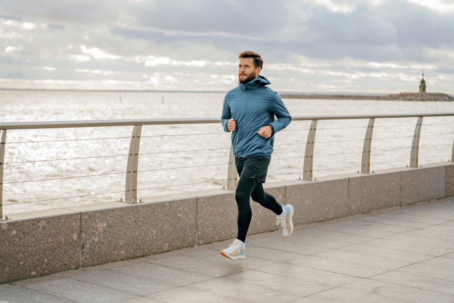 bearded-man-teal-jacket-finds-his-pace-along-waterfront-promenade-clouds-gathering.jpg
