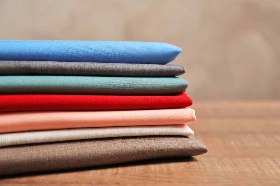 stack-colorful-fabrics-wooden-table-closeup.jpg