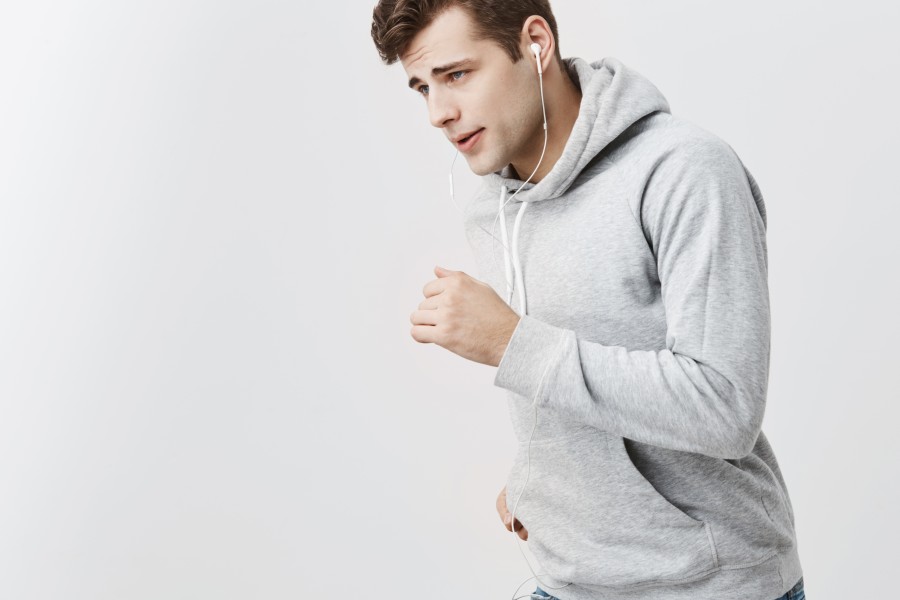 indoor-shot-brunnete-handsome-man-with-blue-eyes-gray-hoodie-jeans-with-earphones-running-against-gray-studio-wall.jpg