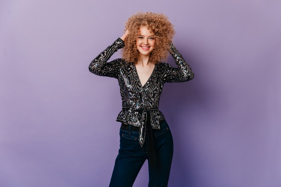 blue-eyed-smiling-girl-touches-her-blond-curls-woman-dark-jeans-shiny-shirt-with-ornament.jpg
